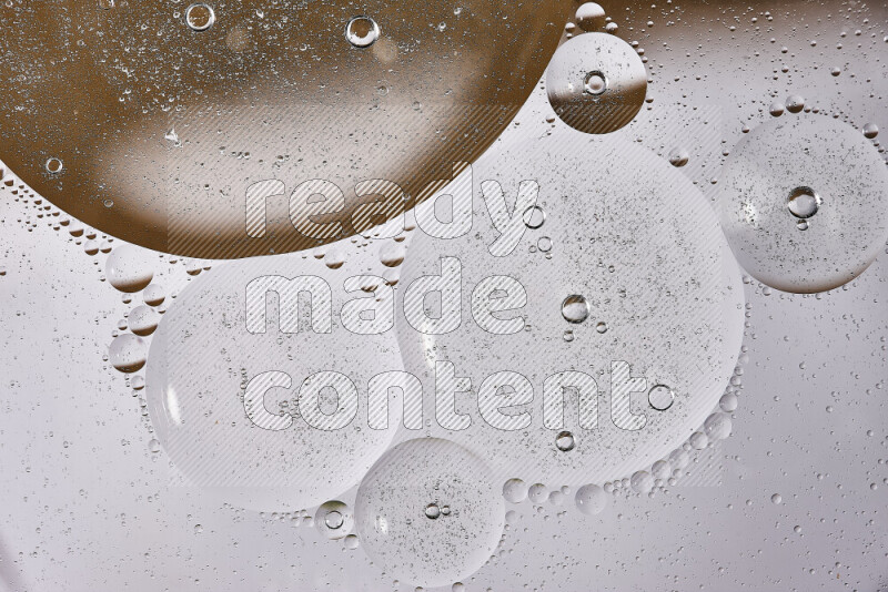Close-ups of abstract oil bubbles on water surface in shades of white and brown