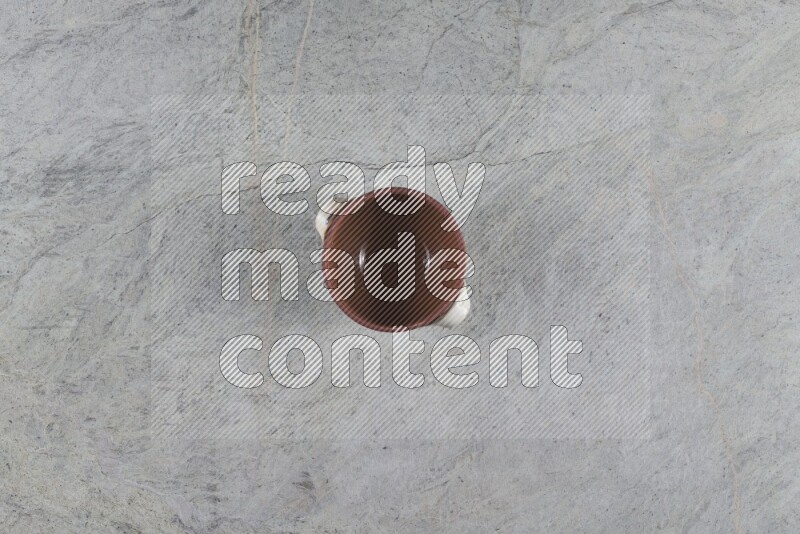 A multicolored pottery pot with its lid on grey marble background