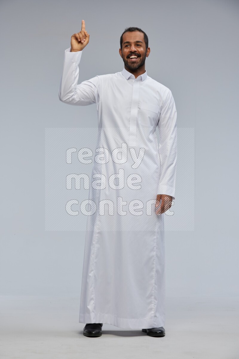 Saudi man Wearing Thob standing interacting with the camera on Gray background