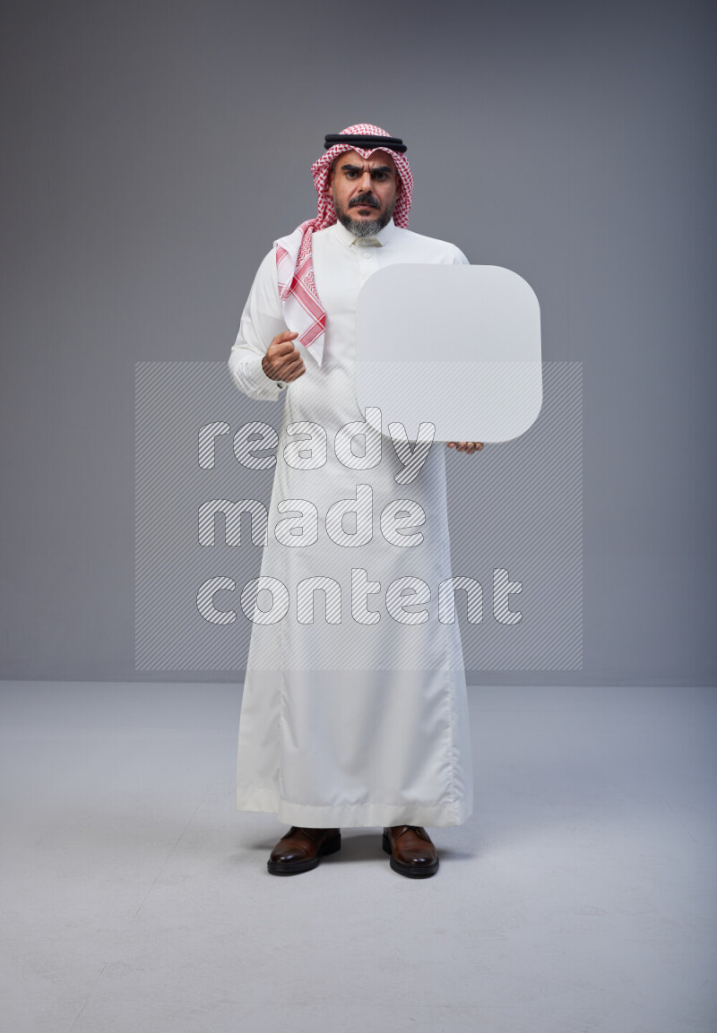 Saudi man Wearing Thob and red Shomag standing holding social media sign on Gray background