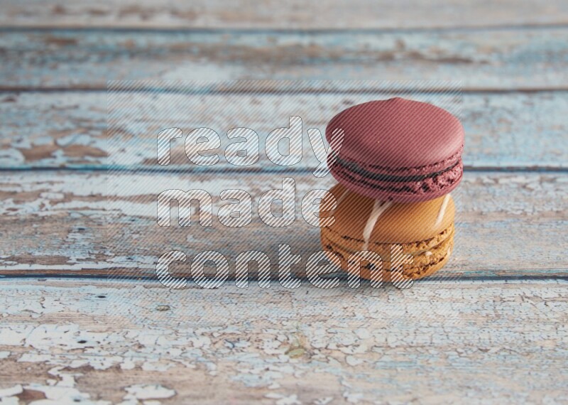 45º Shot of of two assorted Brown Irish Cream, and Red Cherry macarons  on light blue background