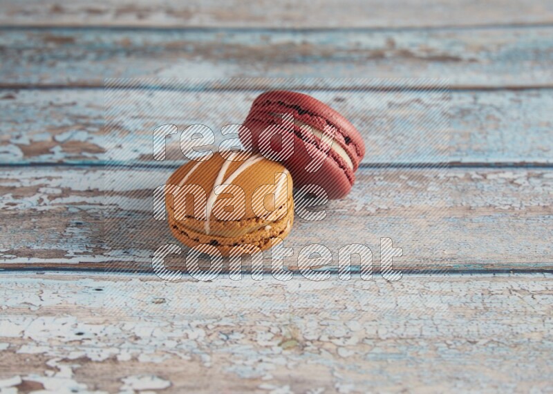 45º Shot of of two assorted Brown Irish Cream, and Red Velvet macarons on light blue background