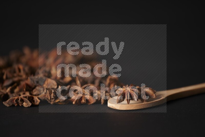 Star Anise in a wooden spoon and spreading on a black flooring