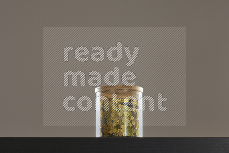 Sequins in a glass jar on black background