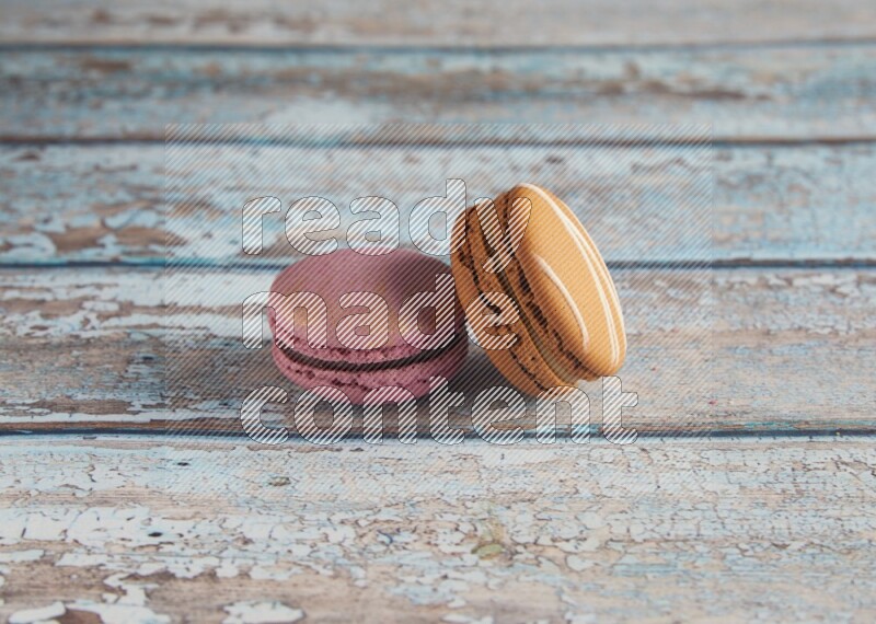 45º Shot of of two assorted Brown Irish Cream, and Purple Strawberry macarons  on light blue background