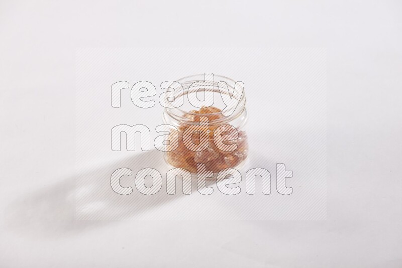 A glass jar filled with gum arabic on white flooring
