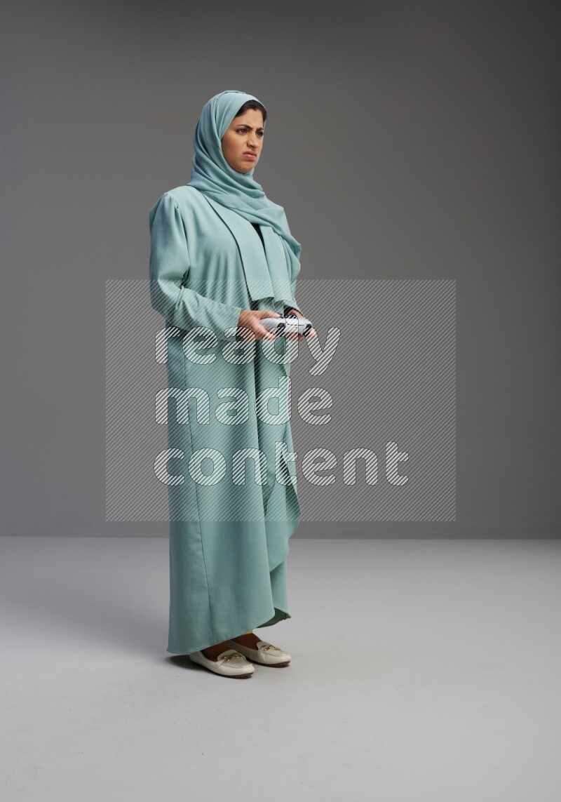 Saudi Woman wearing Abaya standing Playing Games on Gray background