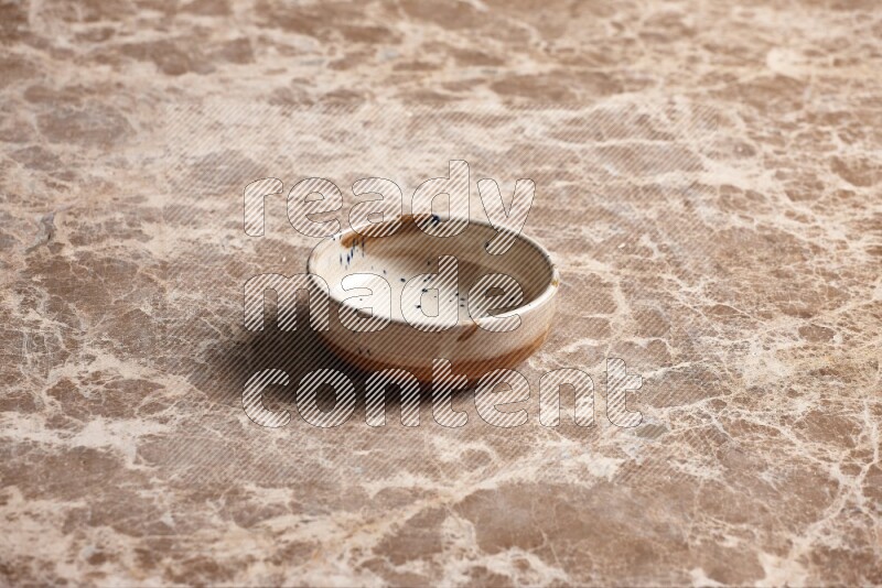A multicolored pottery plate on beige marble background