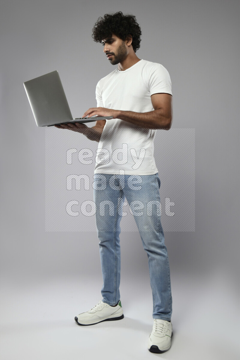 A man wearing casual standing and working on a laptop on white background