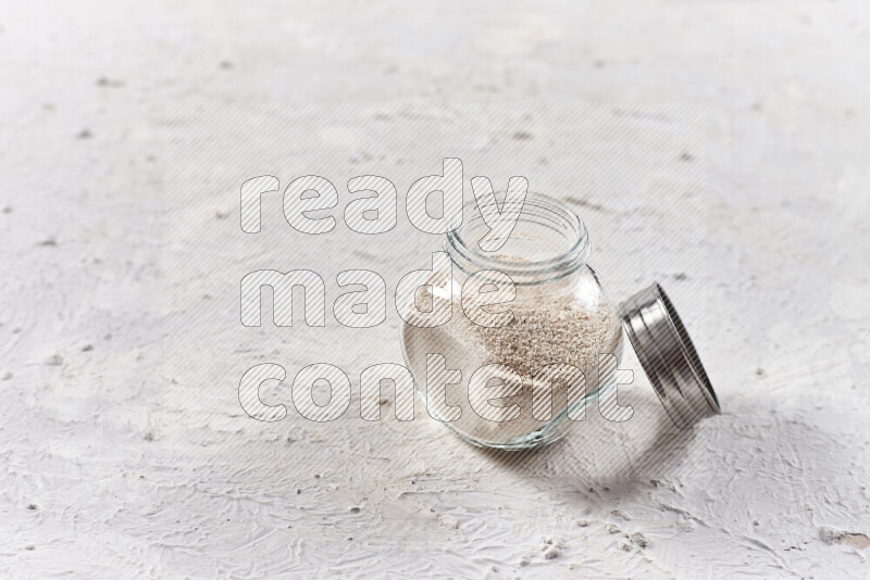 A glass jar full of onion powder on white background