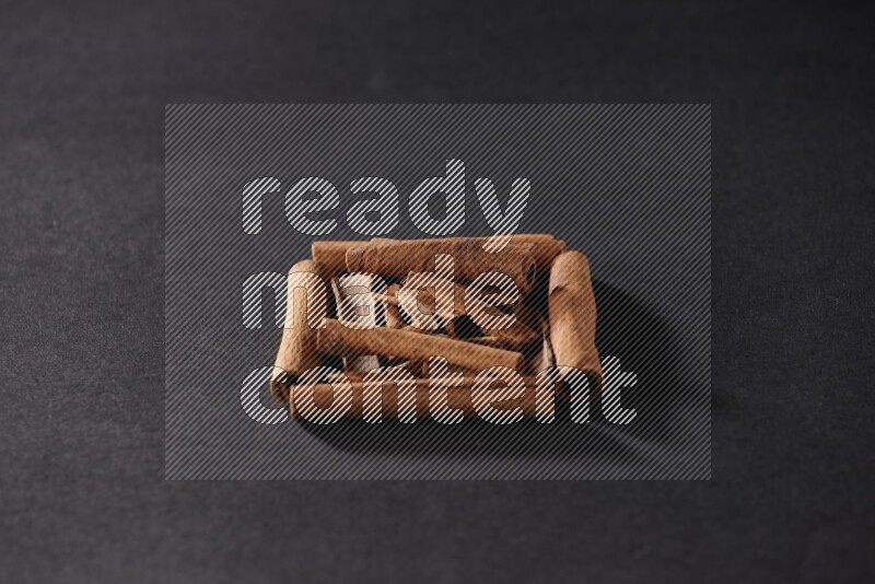 A single square of cinnamon sticks full of cinnamon on black flooring