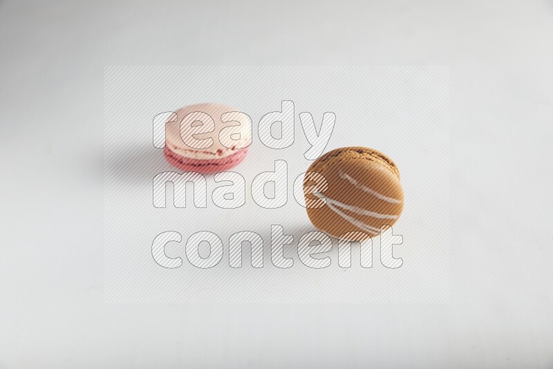45º Shot of of two assorted Brown Irish Cream, and Pink Litchi Raspberry macarons on white background
