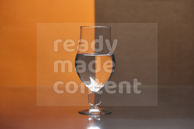 The image features a clear glassware filled with water, set against orange and brown background