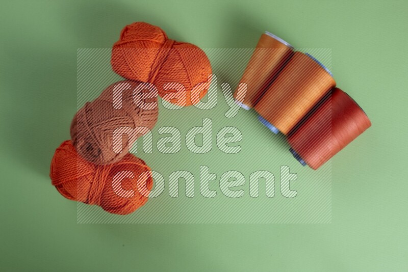 An orange collection of sewing and tailoring tools arranged on a green background