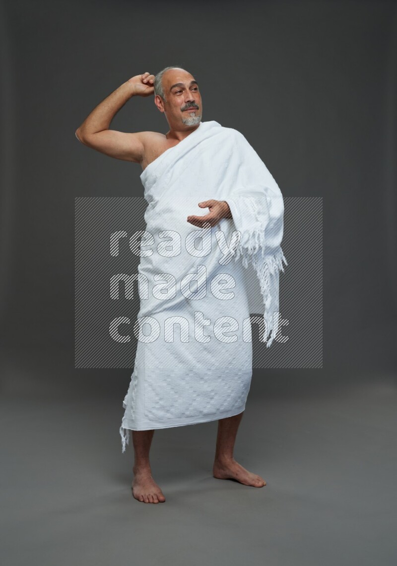 A man wearing Ehram Standing Interacting with the camera on gray background