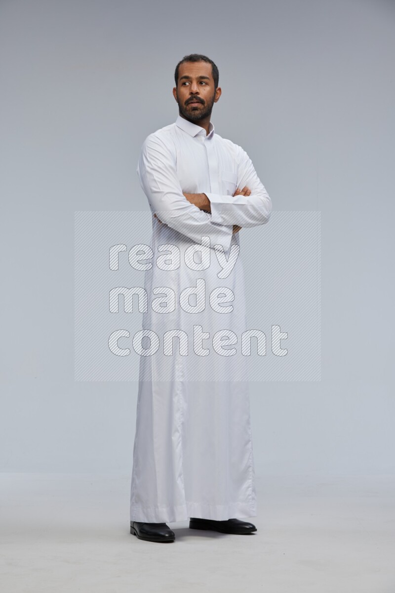 Saudi man wearing Thob standing with crossed arms on Gray background