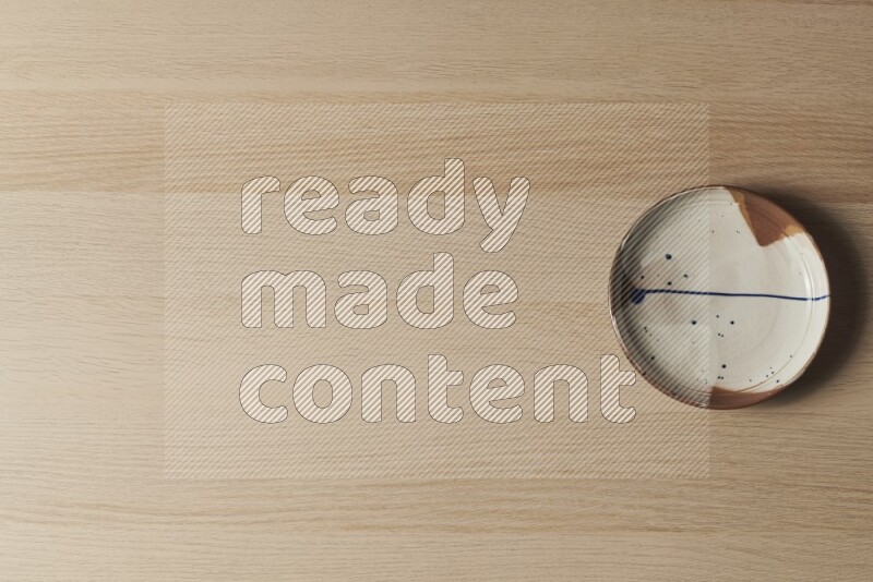 A multicolored pottery plate on light wooden background