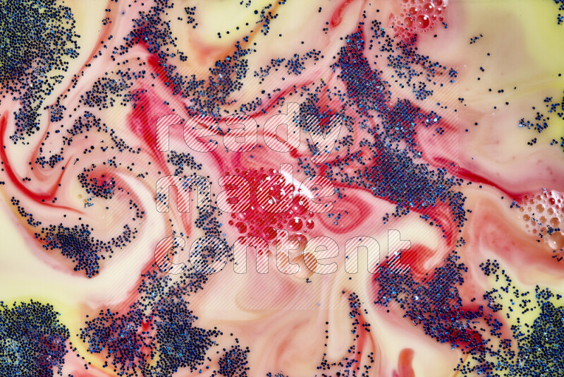 A close-up of sparkling blue glitter scattered on swirling yellow and red background