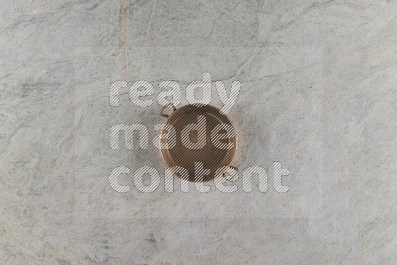 A small copper pan on grey marble background