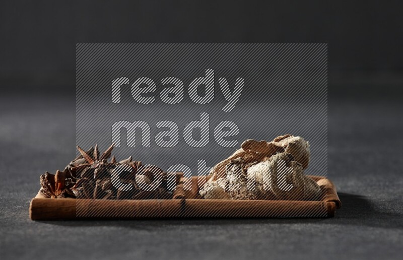 2 squares of cinnamon sticks full of star anise and dried ginger on black flooring