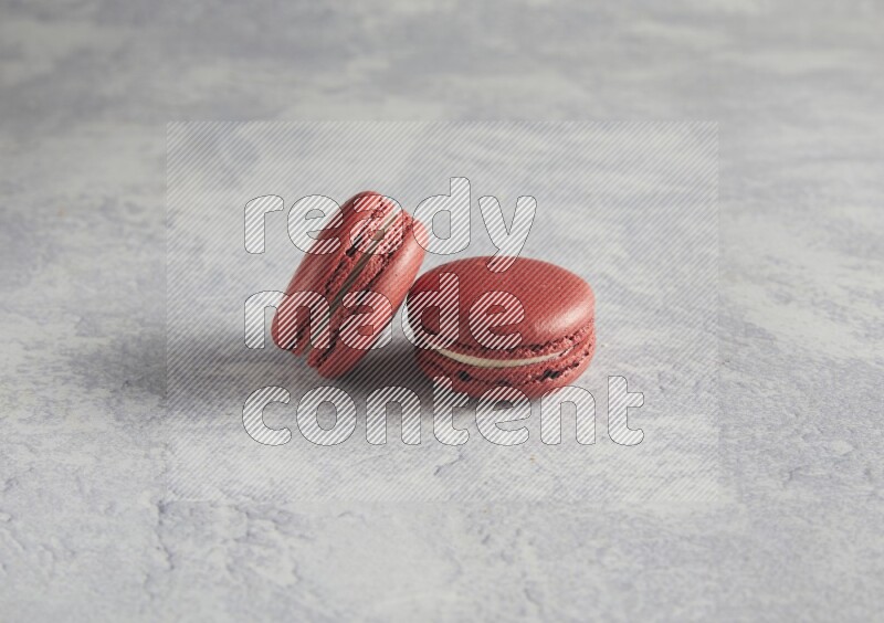 45º Shot of two Red Velvet macarons  on white  marble background