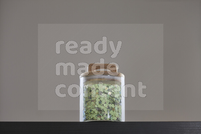 Sequins in a glass jar on black background