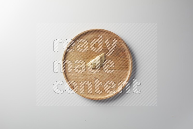 A single Sambosa on a wooden round plate on a white background