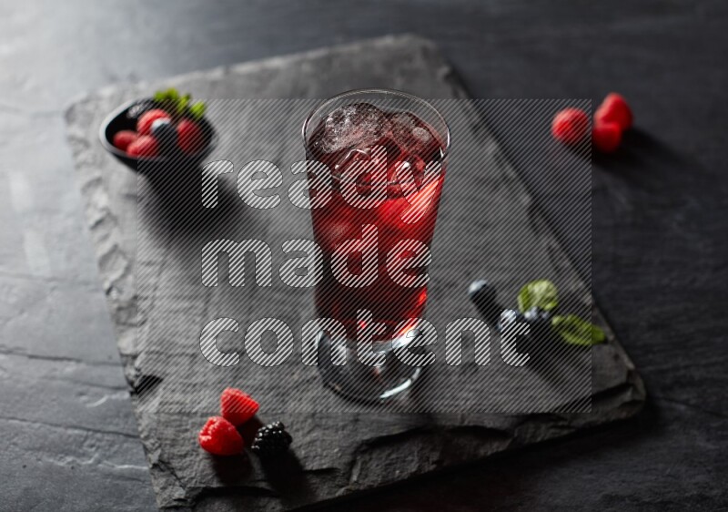 A glass of mixed berries juice on black background