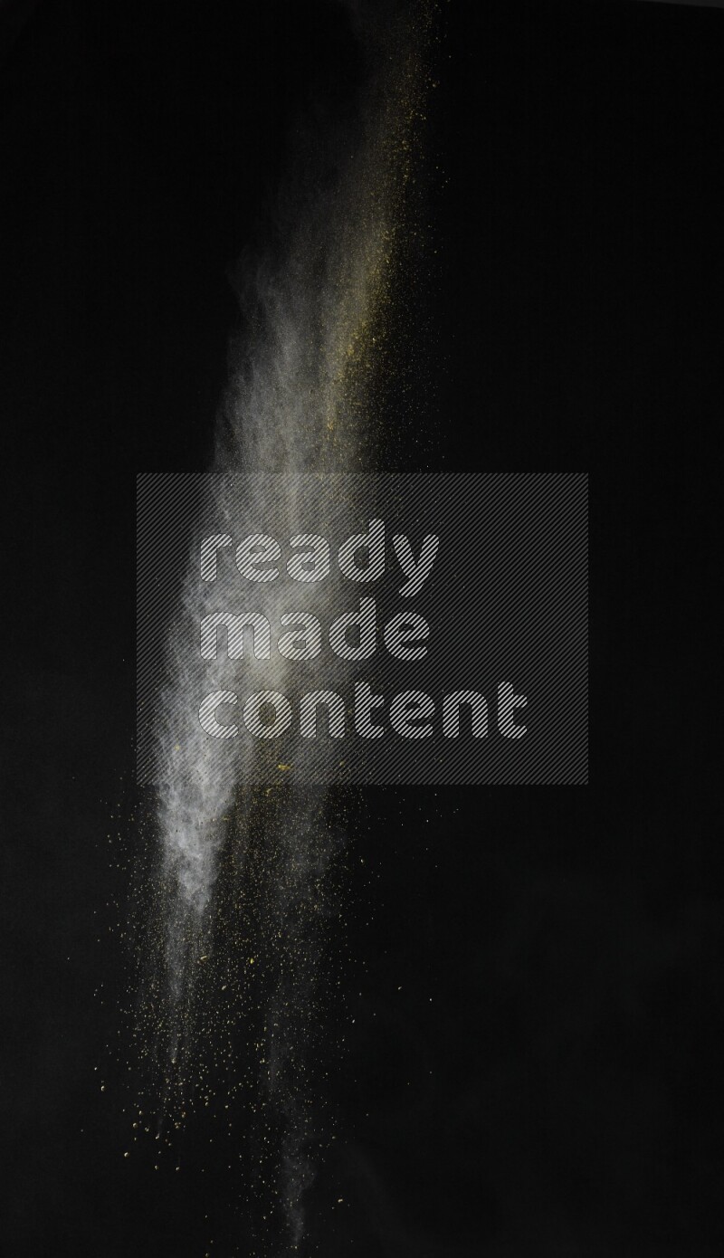 A side view of yellow powder explosion on black background