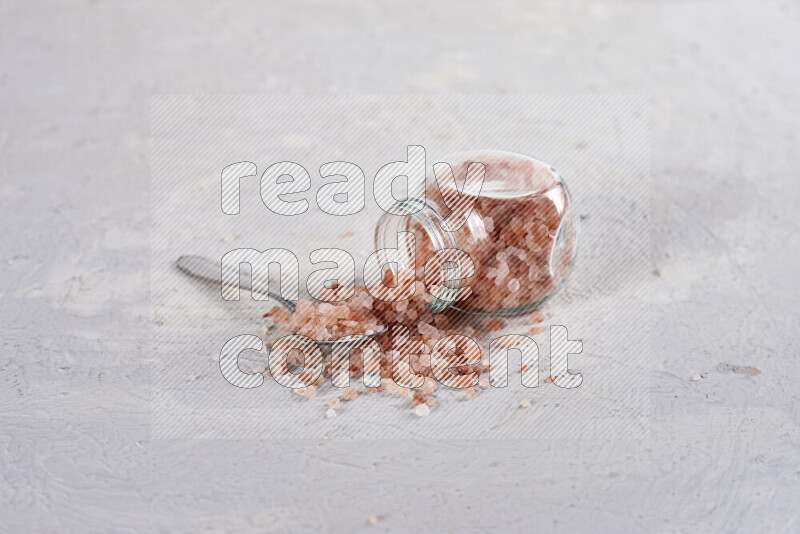 A glass jar full of coarse himalayan salt crystals on white background