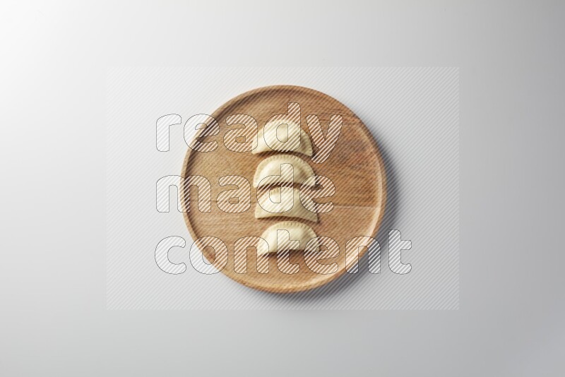 Four Sambosas on a wooden round plate on a white background