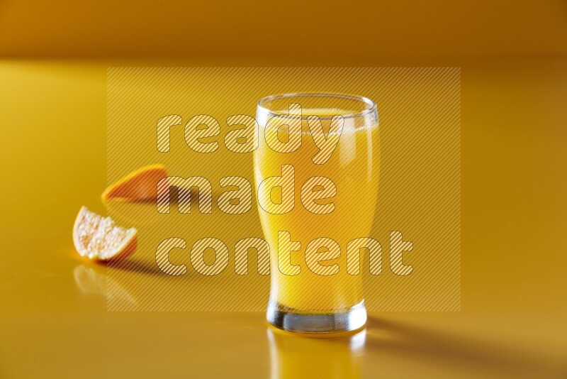 glass of orange juice on yellow background