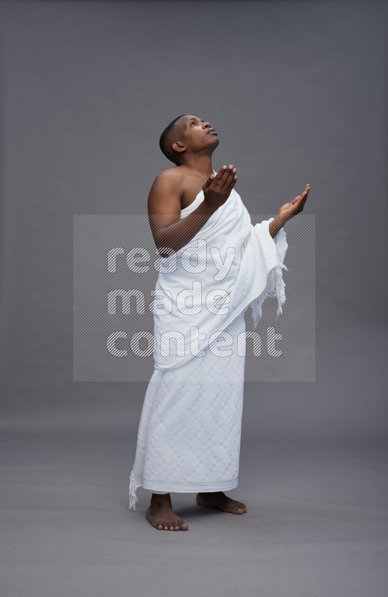A man wearing Ehram Standing dua'a on gray background