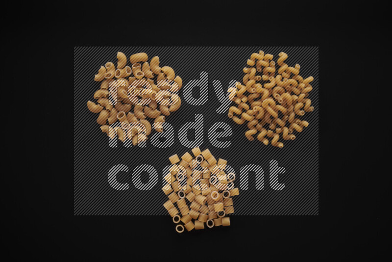 Different pasta types in bunches on black background