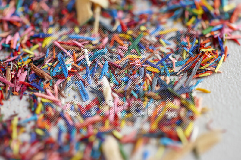 This image showcases a vibrant multicolored pencil shavings scattered on grey background
