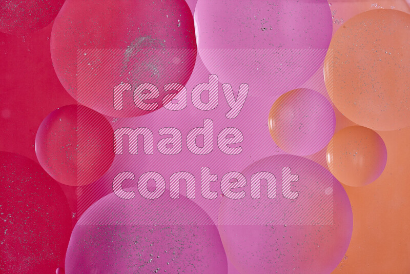 Close-ups of abstract oil bubbles on water surface in shades of red, orange and pink