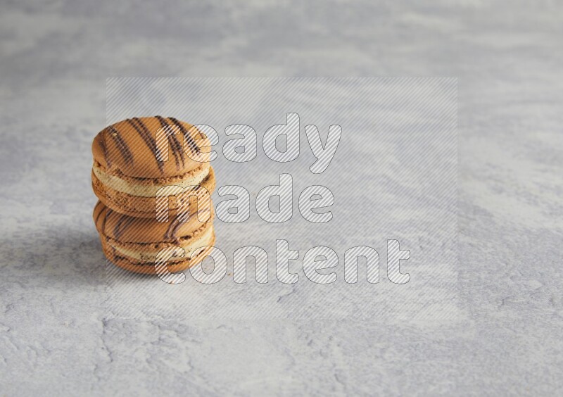 45º Shot of two light brown  Almond Cream macarons  on white  marble background