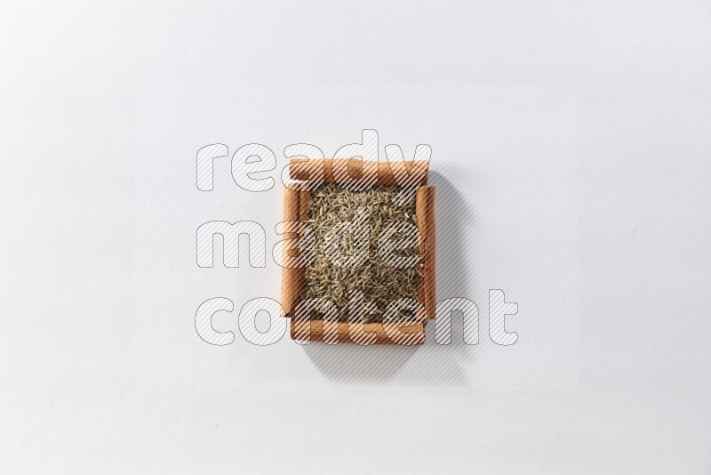 A single square of cinnamon sticks full of cumin on white flooring