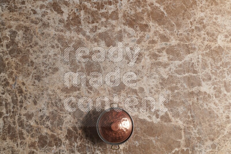 A small copper pot on beige marble background