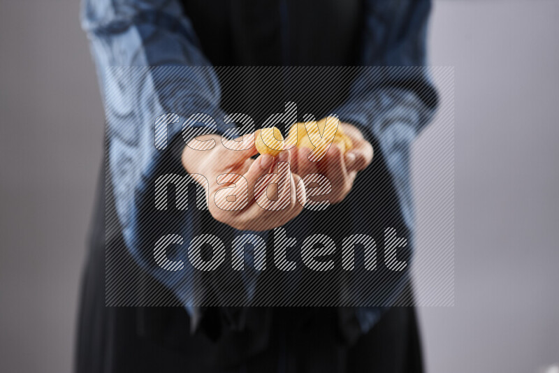 Woman in abaya holding different kinds of snacks in different positions