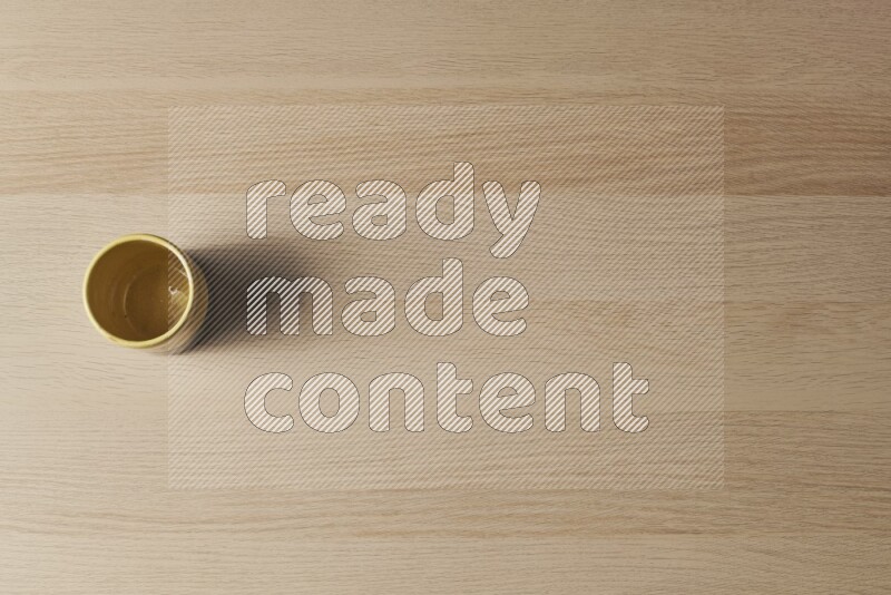 A multicolored pottery cup on light wooden background