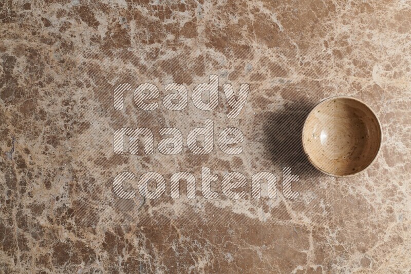 A beige pottery bowl on beige marble background