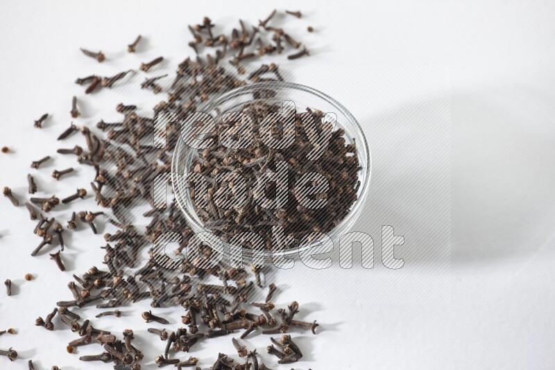 A glass bowl full of cloves on a white flooring