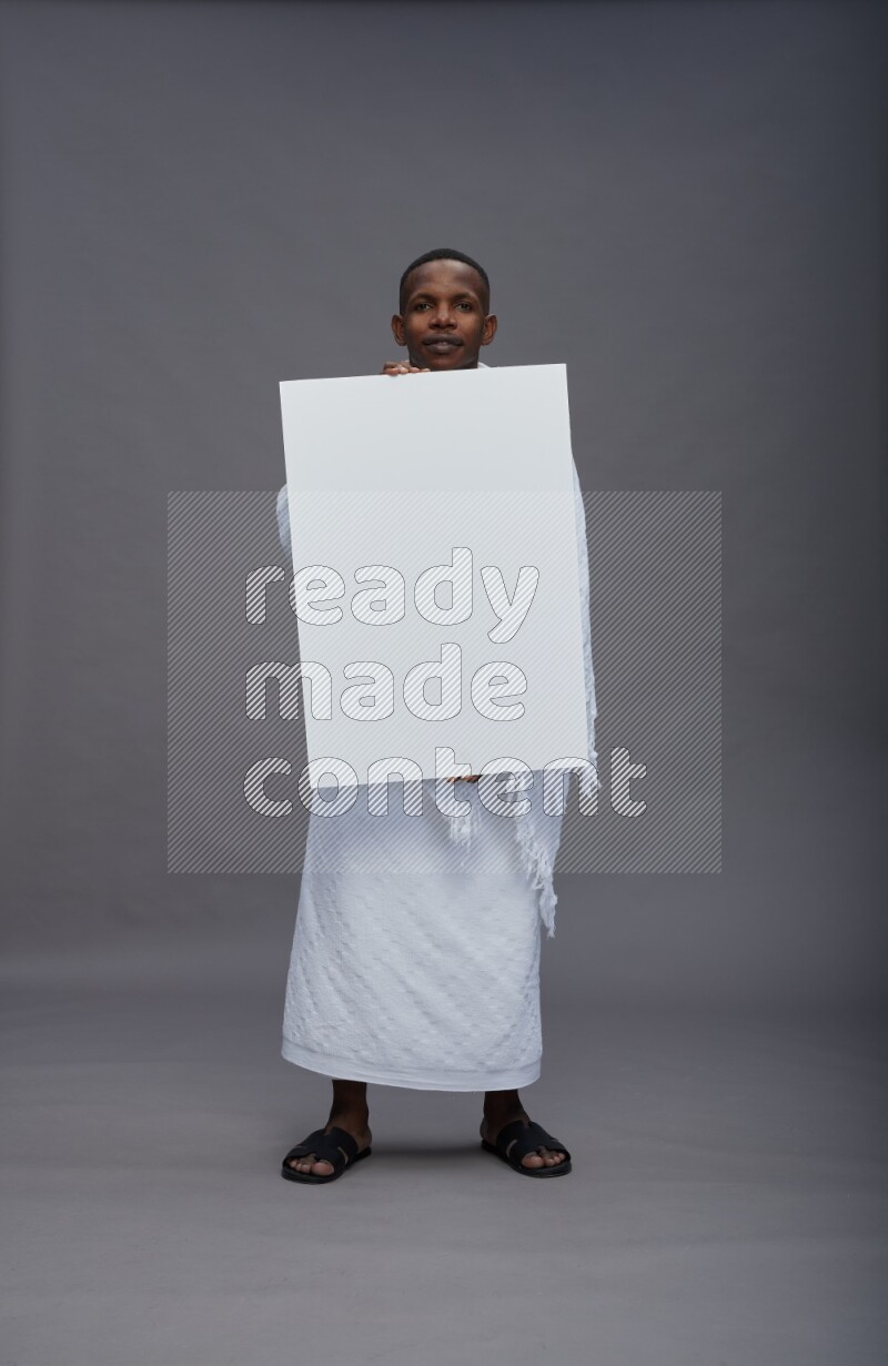 A man wearing Ehram Standing holding board sign on gray background