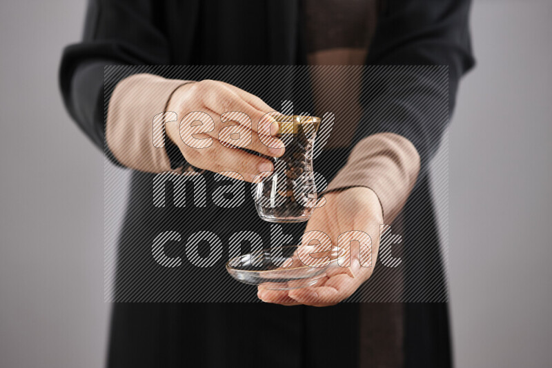 Woman in abaya holding different kinds of coffee beans in different positions