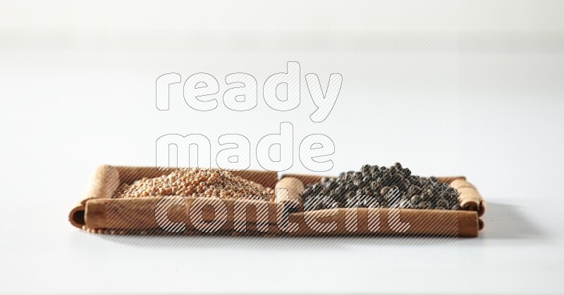 2 squares of cinnamon sticks full of mustard seeds and black peppers on white flooring