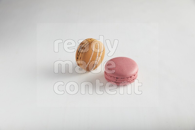 45º Shot of of two assorted Brown Irish Cream, and Pink Raspberry macarons on white background