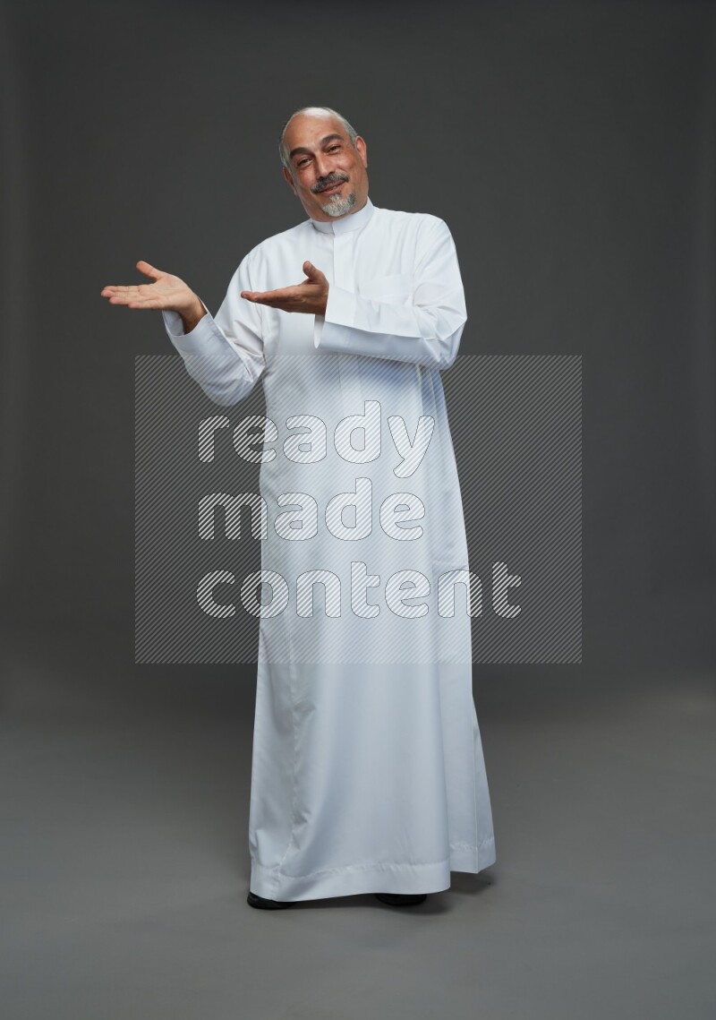 Saudi man without shomag Standing Interacting with the camera on gray background