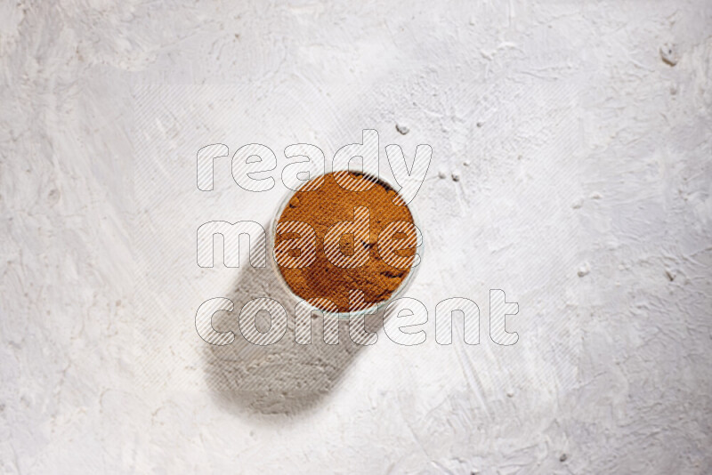 A colored pottery bowl full of ground paprika powder on white background