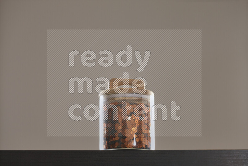 Sequins in a glass jar on black background
